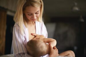 newborn-children-infancy-childcare-motherhood-concept-sleepy-young-mother-with-messy-blonde-hair-breastfeeding-her-infant-son-night-pretty-mom-giving-breast-seven-m